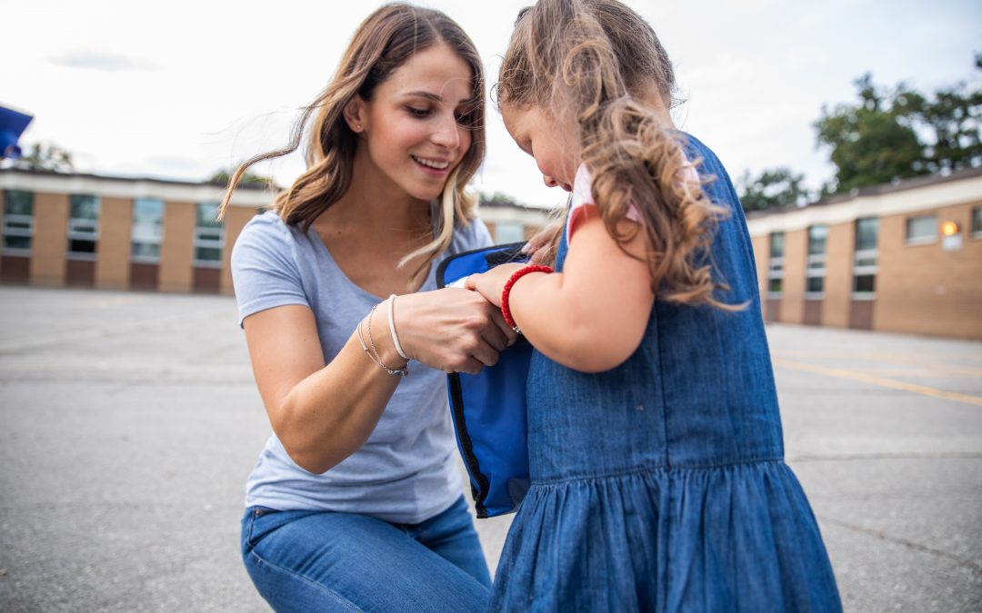 A mom smiles as she drops her young daughter off at school and checks her lunch bag