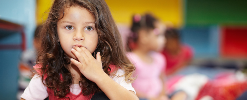 young girl with fingers near mouth acting shy