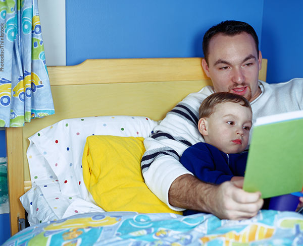 father and son in bed reading