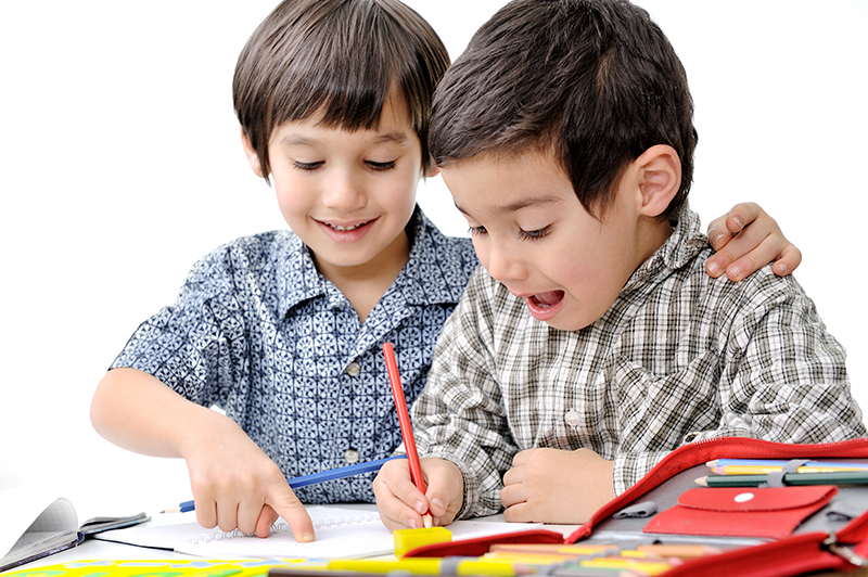 little boy helping friend with writing