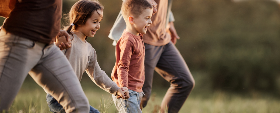 children walking in a field with parents holding hands